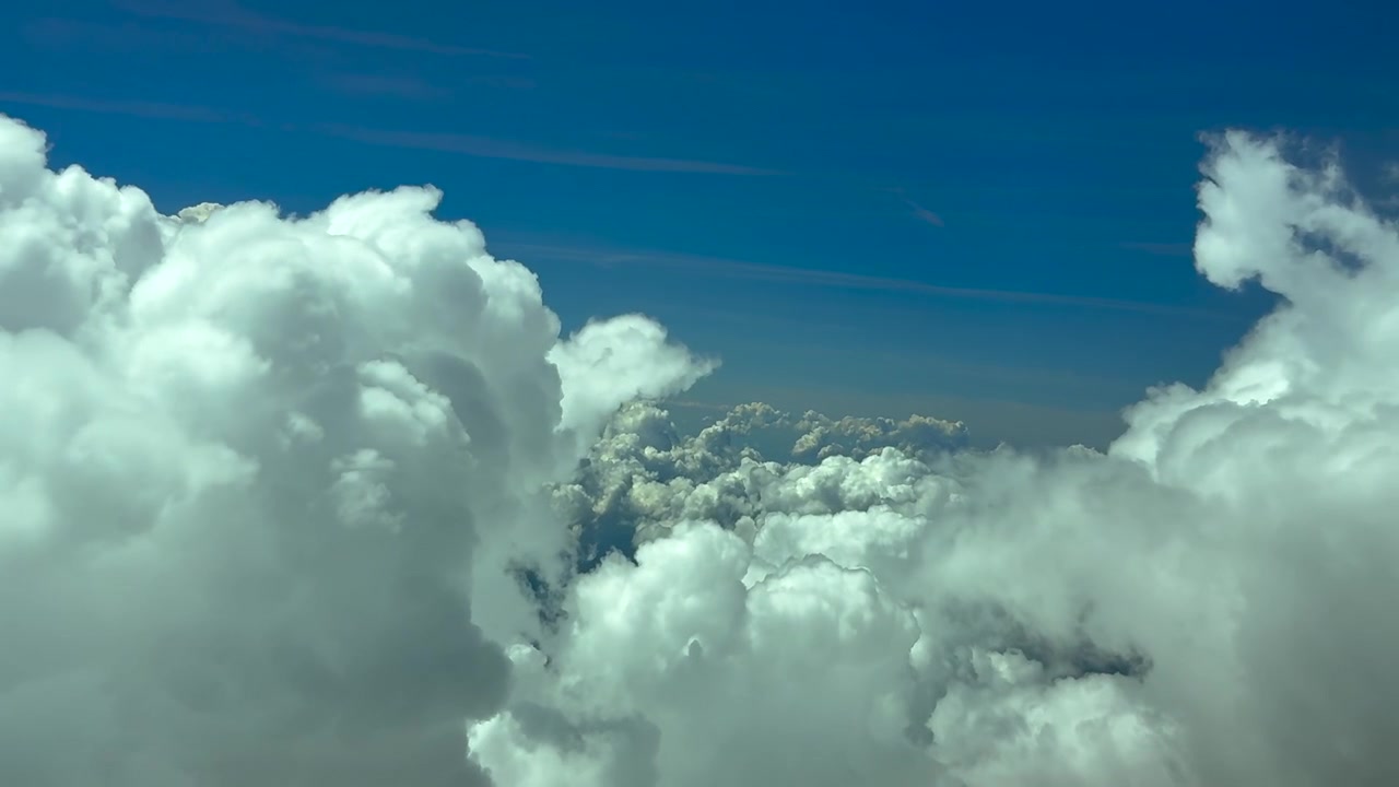 Fordybende pilotperspektiv fra et jetcockpit, der flyver i 12.000 meters højde mellem toppen af truende stormskyer og foretager nogle sving for at undgå turbulens.