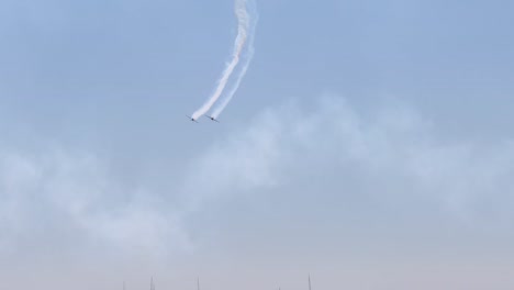 jets create intricate smoke trails in the sky above a distant coastline, showcasing precision and skill.