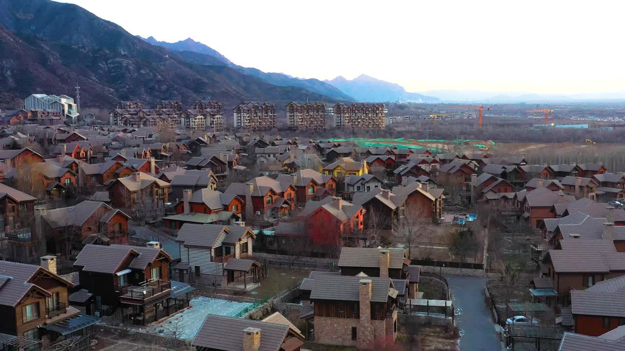 vista aérea de jackson hole, una ciudad de copia china cerca de beijing, china. bañada en cálidos tonos de puesta de sol. cuenta con casas encantadoras, vastos paisajes y montañas lejanas.