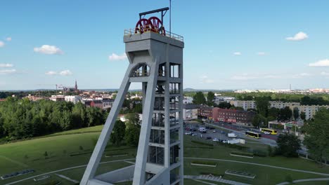 Historical-mine-shaft-during-a-beautiful-summer-day-surrounded-by-lush-greenery,-grass,-and-trees-under-a-blue-sky