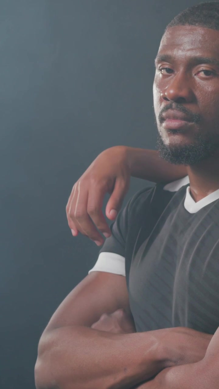 Verticale video: Reagerend op een cameracue, man die zijn hoofd beweegt en armen kruist in een studio met een jersey-waas