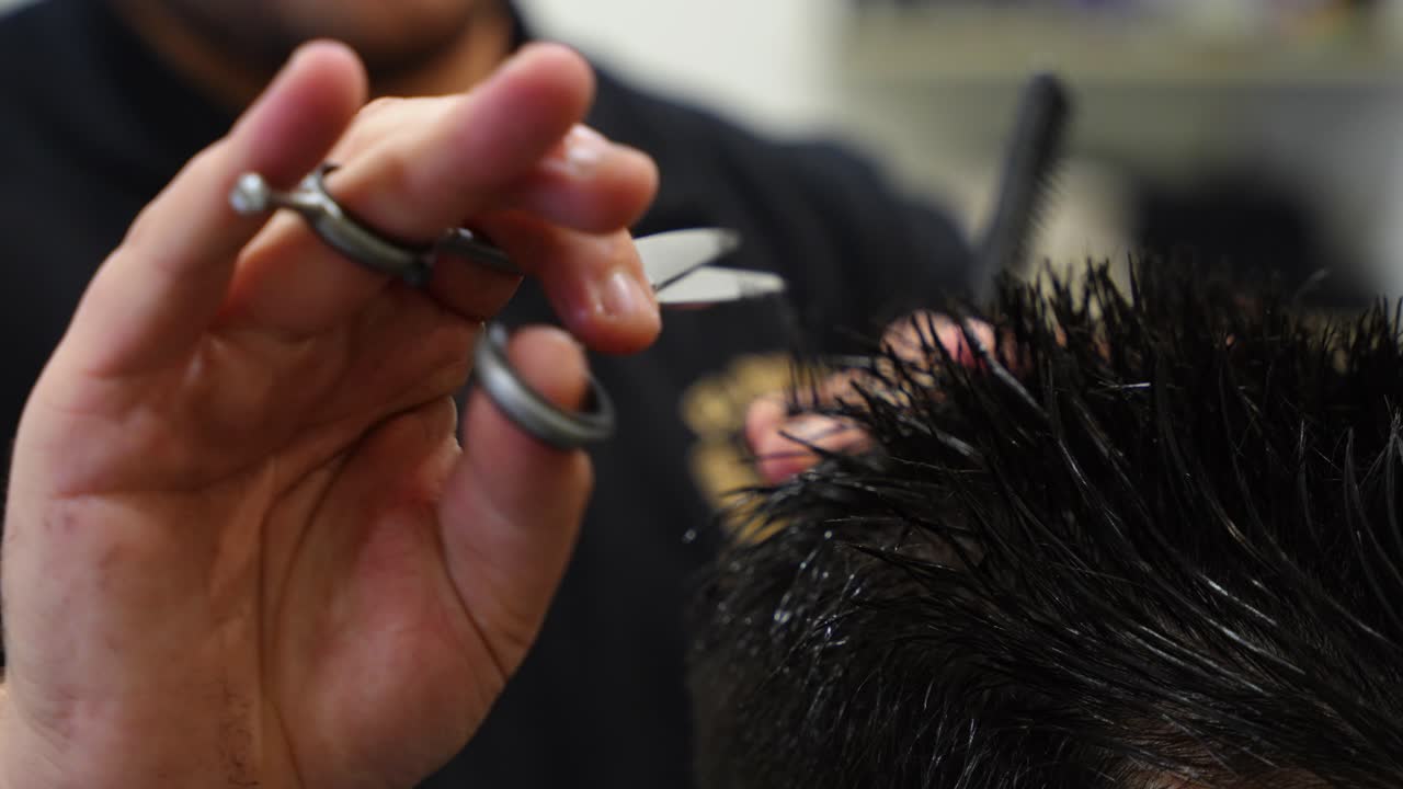 Close up of hairdresser hands using scissors and comb with precision to cut client hair