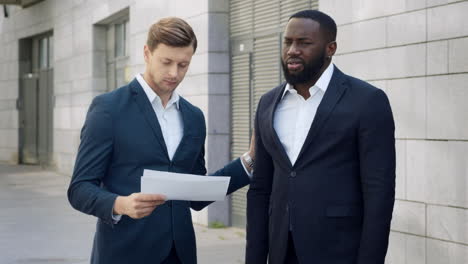 upset businessmen looking bad work results on documents outdoors