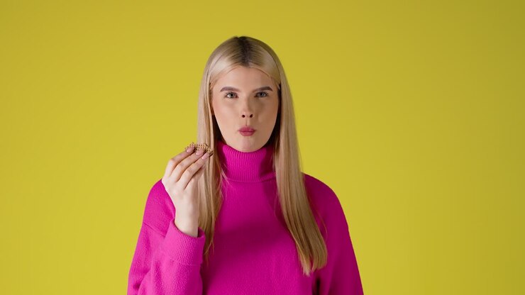 Attractive Blonde Woman Eating Wafer and Looking At Camera, Studio Portrait