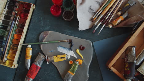 artist's workspace with paints, brushes, and palette