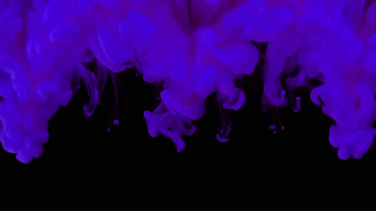 Goccioline di inchiostro viola che si dissolvono nell'acqua su sfondo nero