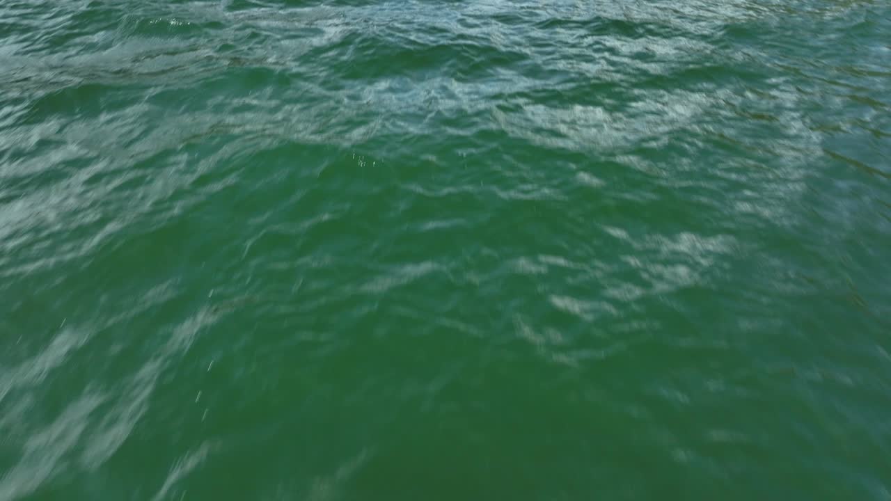 Gentle waves ripple across emerald green water in an outdoor natural setting