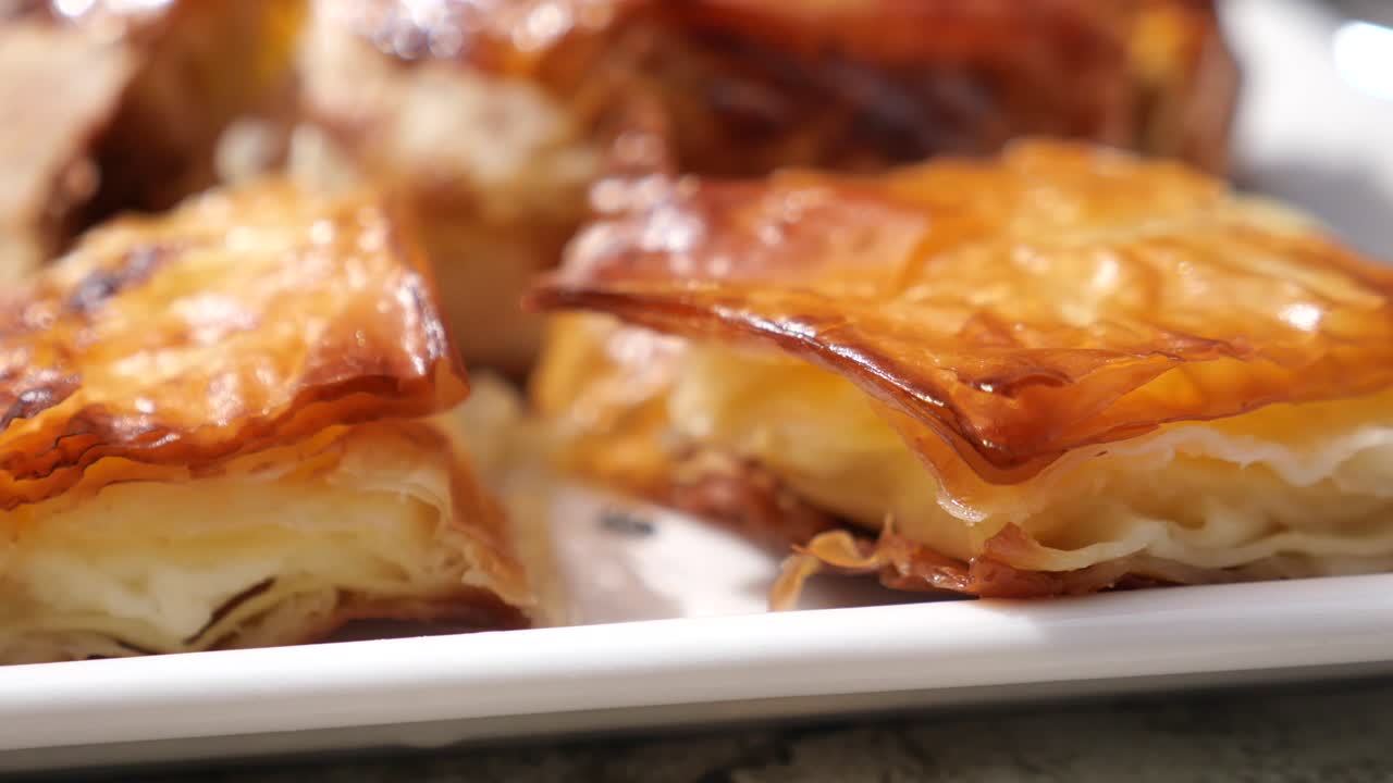 Close-up of golden, flaky pastries on a white plate