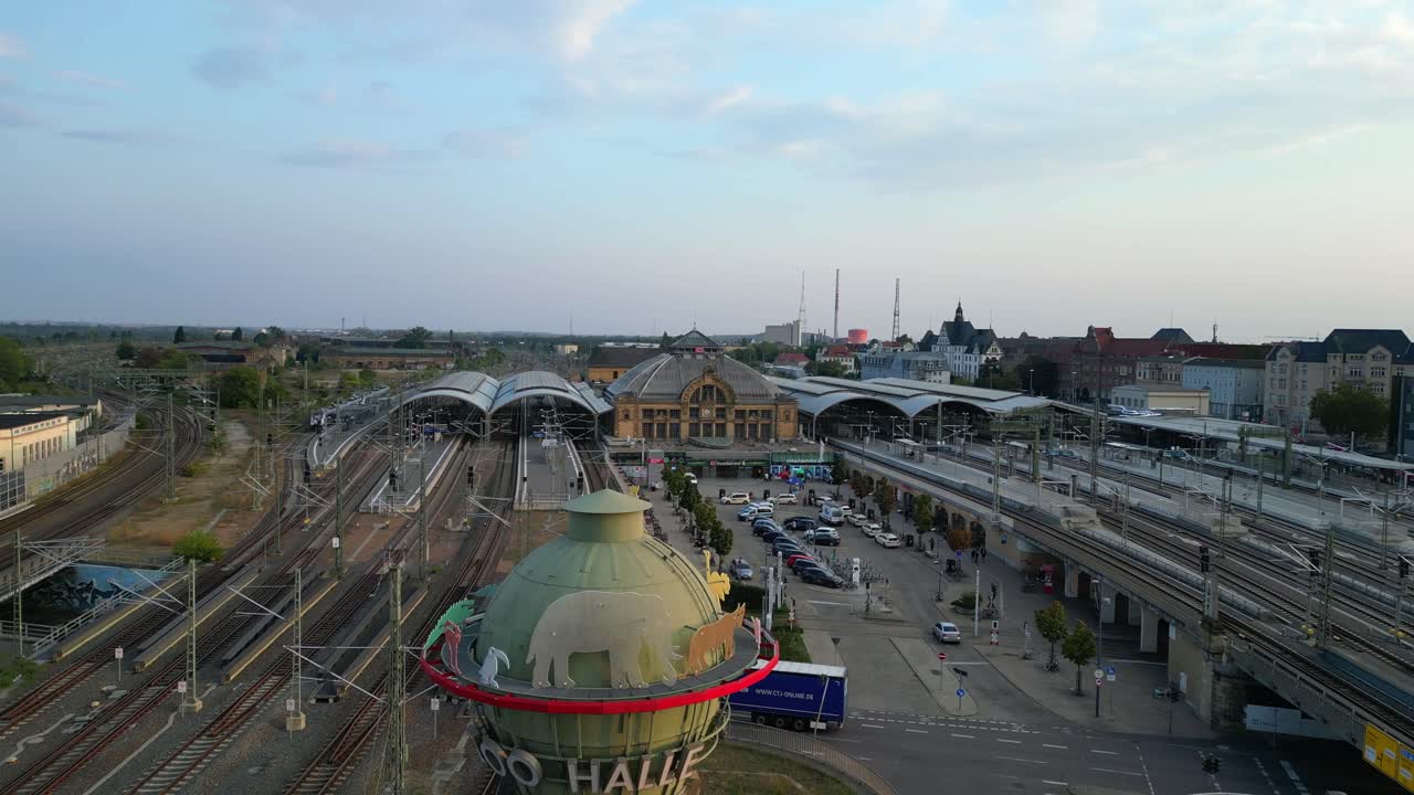 Aerial view of a modern train station with connecting tracks leading to suburbs and the city center. Beautiful aerial view flight fly reverse drone