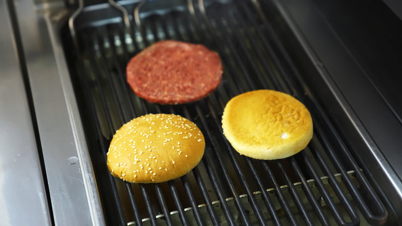 Chef preparing burgers at kitchen. Mixed american barbecue food on hot grill