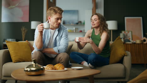 calm pair talking sofa drinking morning espresso home. resting woman taking cup