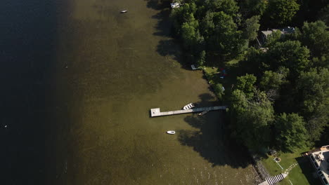 Vista-De-Pájaro-En-ángulo-Alto-De-Muelles-Privados-En-La-Orilla-Poco-Profunda-Del-Lago-Con-Una-Densa-Copa-De-árboles