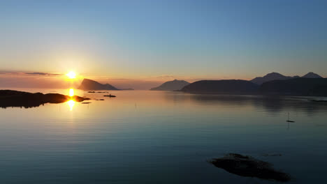 Aerial-view-low-over-serene-ocean,-nightless-night-in-Sommaroya,-North-Norway