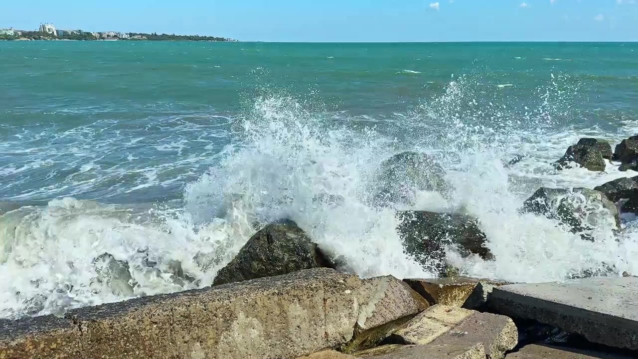 Onde si infrangono contro le rocce sulla riva durante una giornata luminosa in una zona costiera