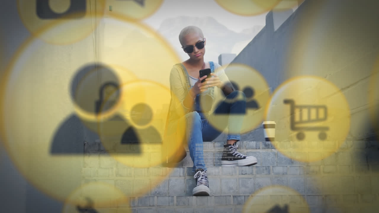 Animation of social media icons and data processing over biracial woman using smartphone
