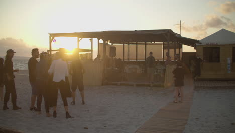 establishing view of group of friends enjoying beach party at sunset, zoom in