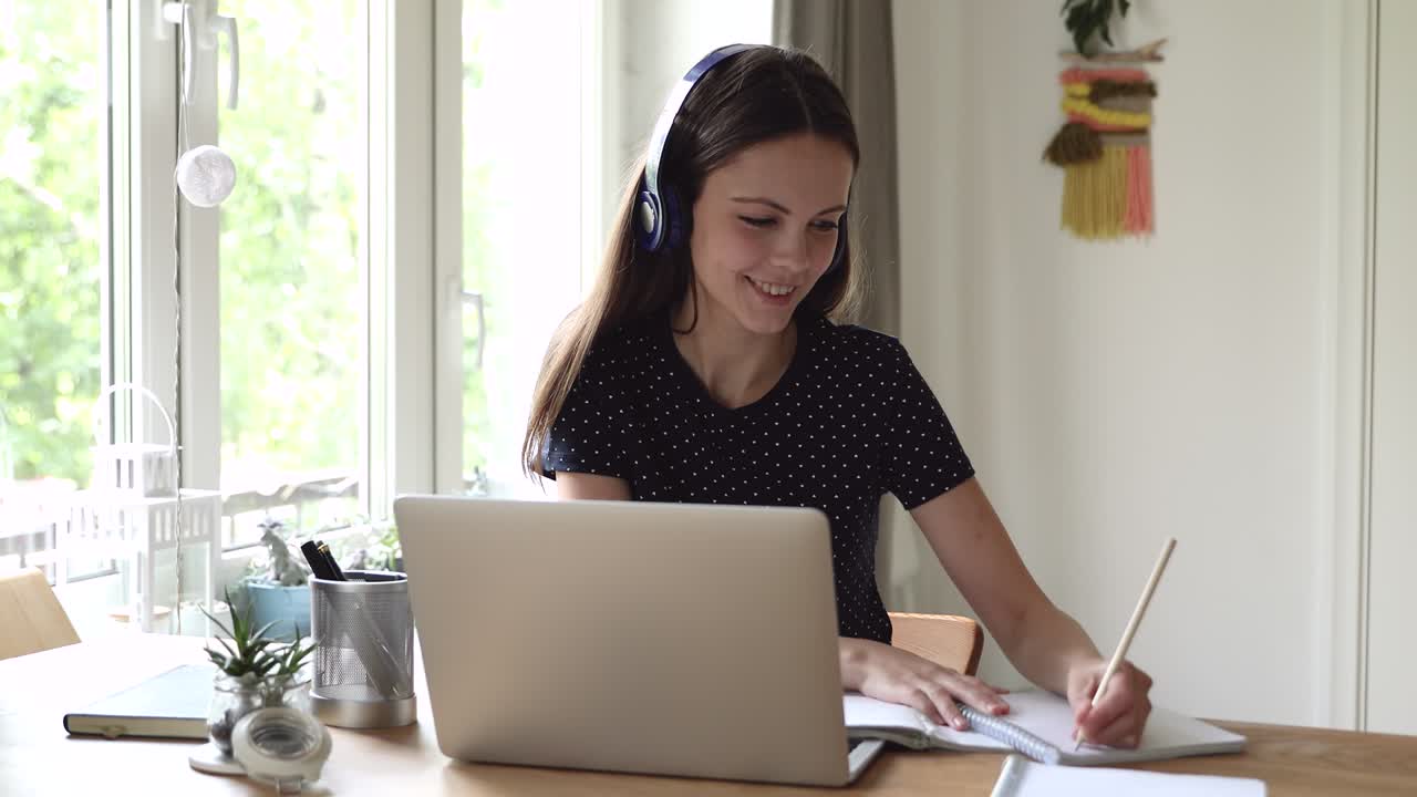 Smiling young beautiful woman studying remotely.