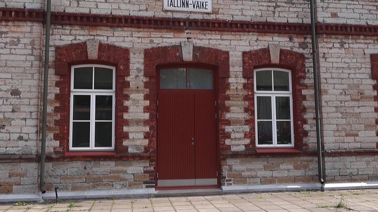 Vecchia facciata in mattoni della storica stazione ferroviaria di Tallinn-Väike nella capitale dell'Estonia, un bellissimo esempio di architettura dei primi del XX secolo in una giornata di sole, con inquadratura inclinata.