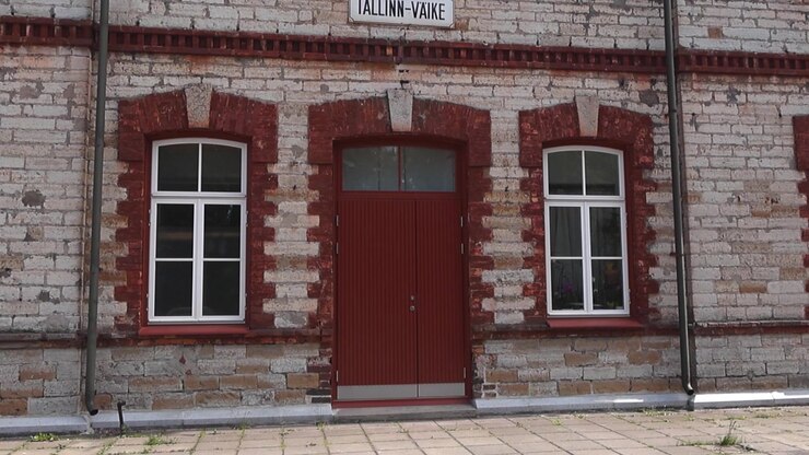 Vecchia facciata in mattoni della storica stazione ferroviaria di Tallinn-Väike nella capitale dell'Estonia, un bellissimo esempio di architettura dei primi del XX secolo in una giornata di sole, con inquadratura inclinata.