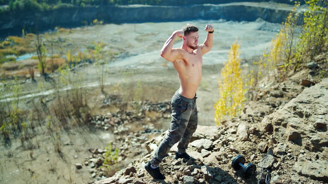 Portrait of shirtless man outdoors. Handsome sporty athlete posing in front of a camera and showing his defined muscles on rocky background.