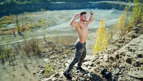 portrait of shirtless man outdoors. handsome sporty athlete posing in front of a camera and showing his defined muscles on rocky background.
