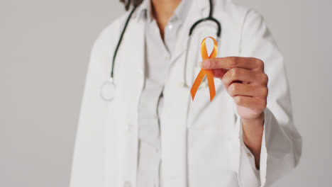 video of smiling biracial female doctor holding orange kidney cancer ribbon