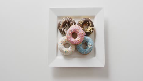 Video-of-donuts-with-icing-on-white-plate-over-white-background