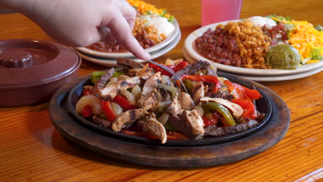 hand takes forkful of sizzling combo fajita platter, push slider slow motion 4k