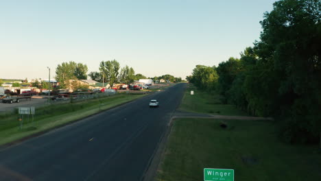 aerial view of white suv driving past 'winger' sign in small minnesota town