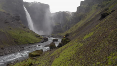 Aerial:-Flying-towards-one-person-standing-on-a-rock,-looking-at-Haifoss-waterfall