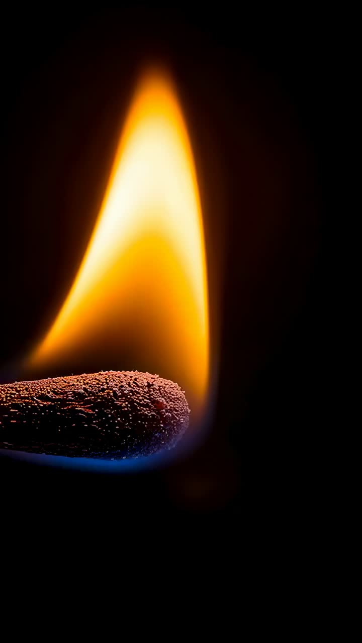 Vertical video: Spark igniting match head, orange flame rising in macro with blue base, grainy tip