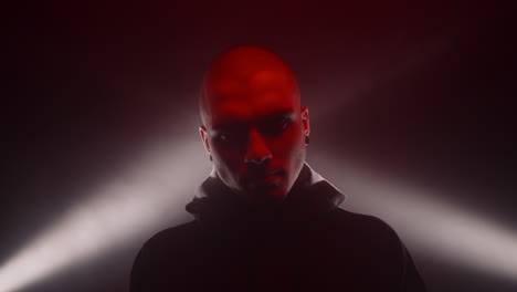 bald man in hoodie with dramatic red and white lighting