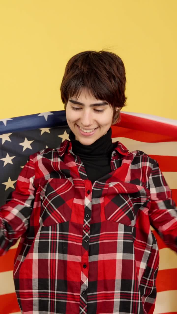 Young Person Wrapped in American Flag Smiling on Yellow Background