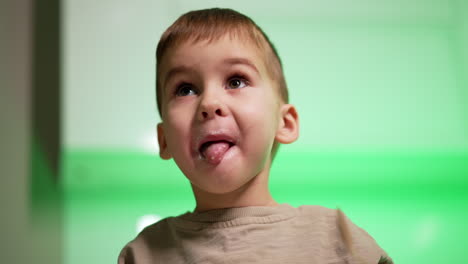 caucasian toddler holding a spoon in his mouth. low angle view at the baby boy eating yogurt.