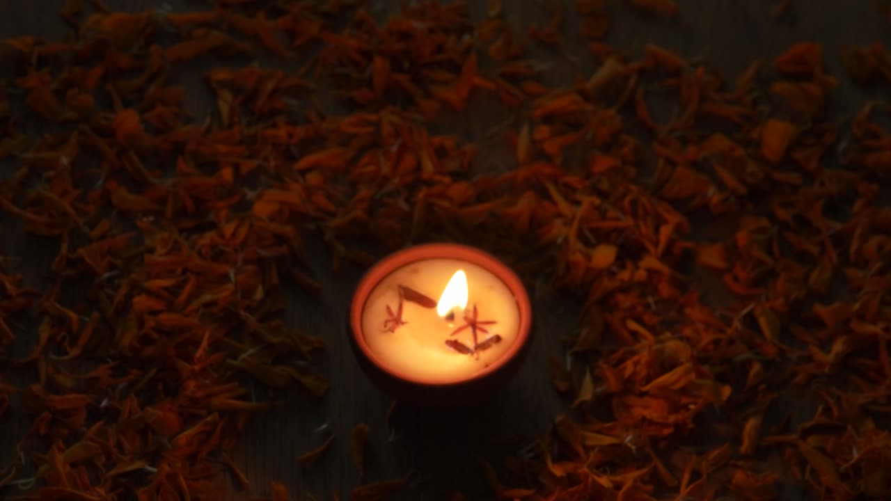 Inquadratura che si abbassa e si allarga su una Diya accesa o una lampada tradizionale usata per varie celebrazioni festive indù, come la festa delle luci Diwali e altre come Dussehra, o per preghiere a casa o in un tempio