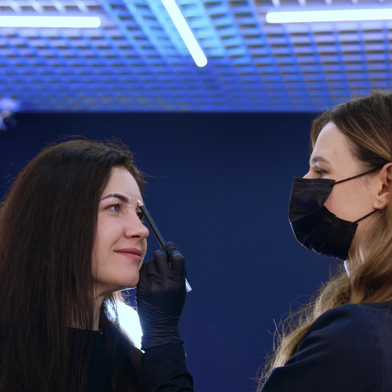 Cosmetologist drawing marks on the woman's face. Client is prepared for the permanent eyebrow make up