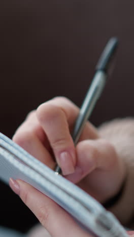 primer plano de la mano tomando notas en un cuaderno mientras lleva un cómodo suéter de punto, el fondo de enfoque suave crea una atmósfera cálida y enfocada, ideal para estudiar, escribir un diario o planear
