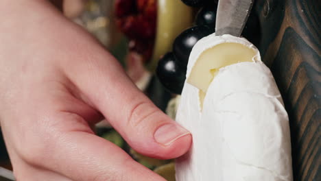 cutting brie cheese on a charcuterie board