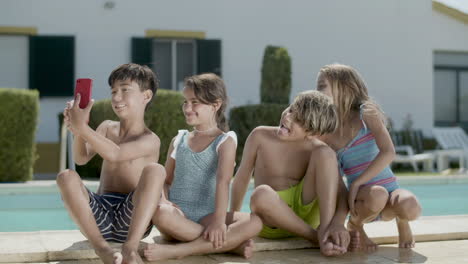 happy children making selfie outside sitting on edge of pool.