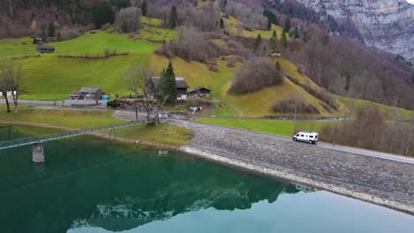 aerial tracking a camper van driving over a dam next to a lake in the alps, switzerland