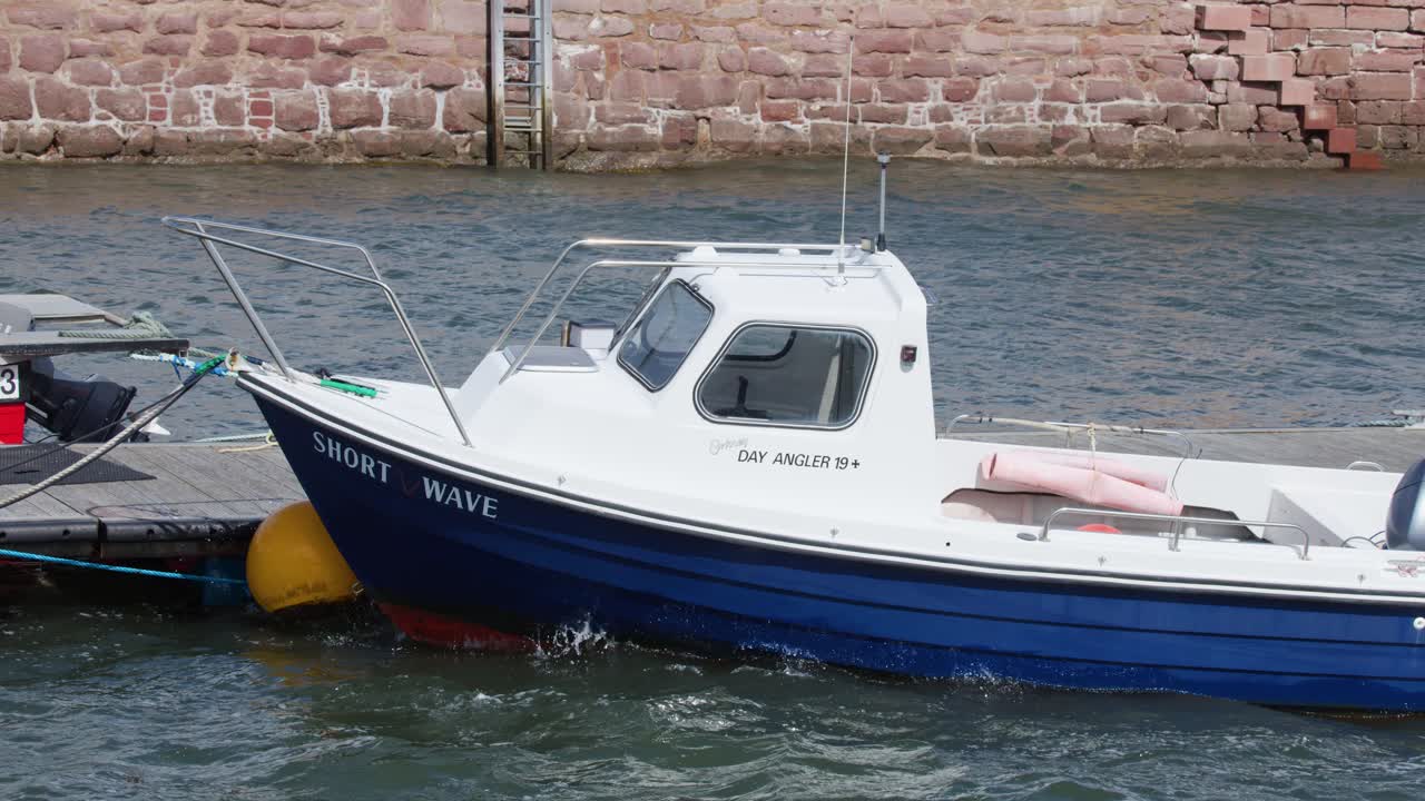Small fishing vessel gently rocking beside dock, daylight, overcast sky, steady camera, Cromarty harbor