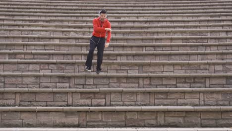 young man listens to music on headphones and dances outdoors.