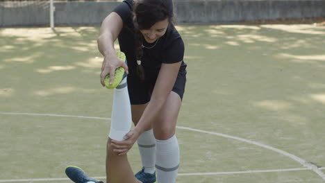 female football player doing exercises for flexibility with help of friend on the field