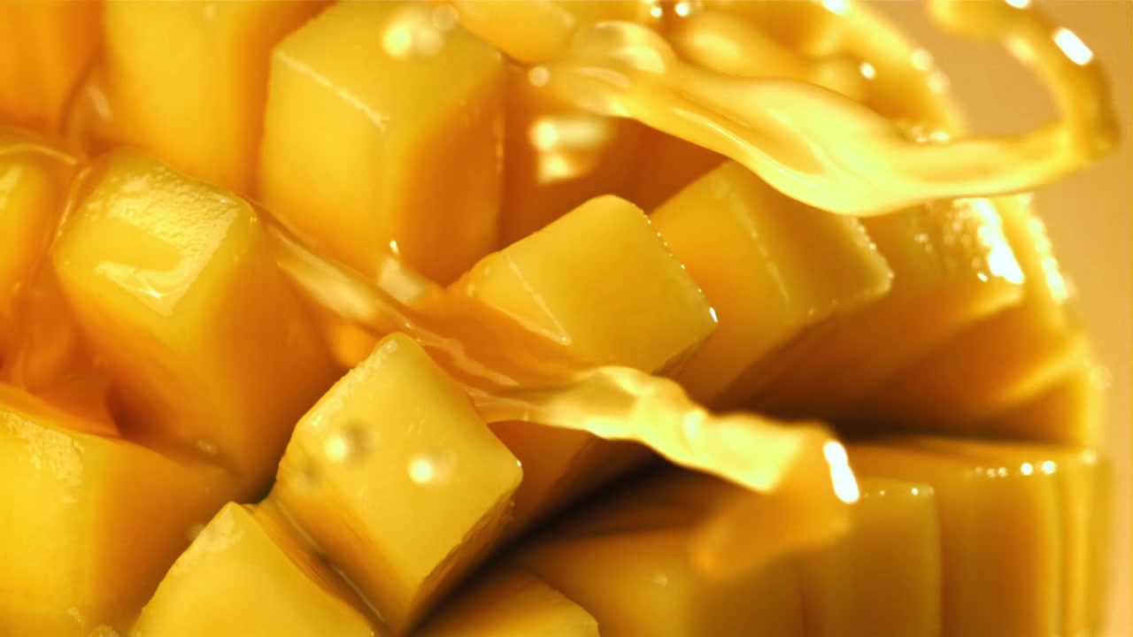 Gyllen sirup helles over fersk terningkuttet mango i sakte film