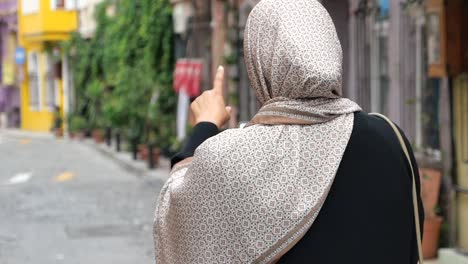 woman in hijab pointing in a colorful street