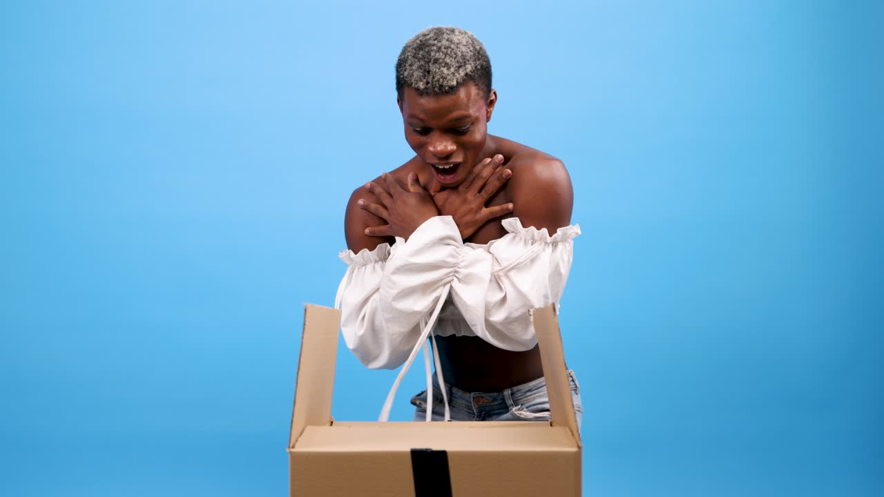 Young Woman Reacting with Surprise and Delight While Unboxing a Package