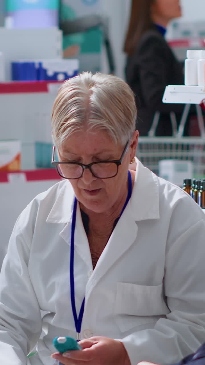 Vertical video Aged pharmacist checks blood glucose