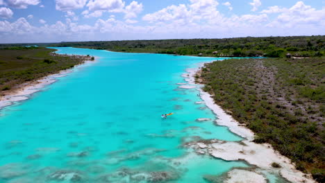 Aufschlussreiche-Drohnenaufnahme-Von-Kajakfahrern-Im-Klaren-Blauen-Wasser-Von-Bacalar,-Mexiko