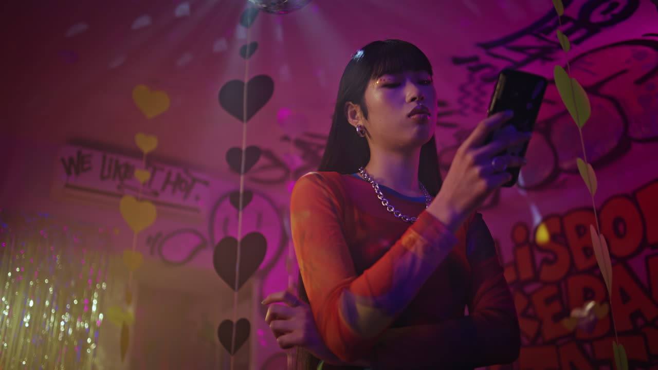 Partying woman using cellphone in nightclub closeup. Young millennial texting