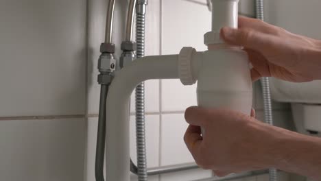hombre quitando la trampa de olores debajo del lavabo del baño